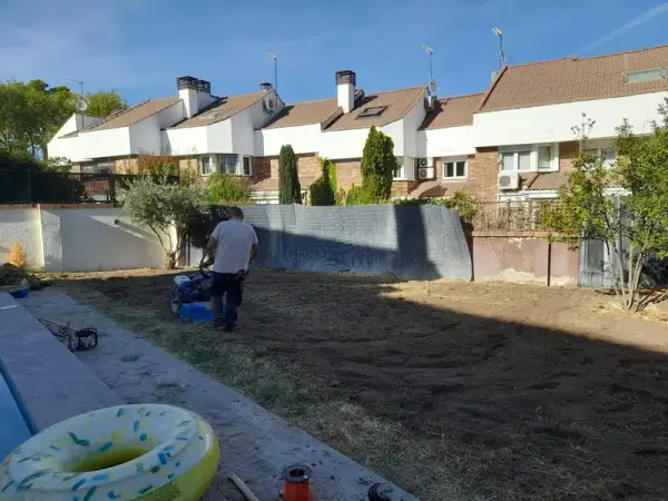 Operario preparando el terreno con motoazada junto a una piscina