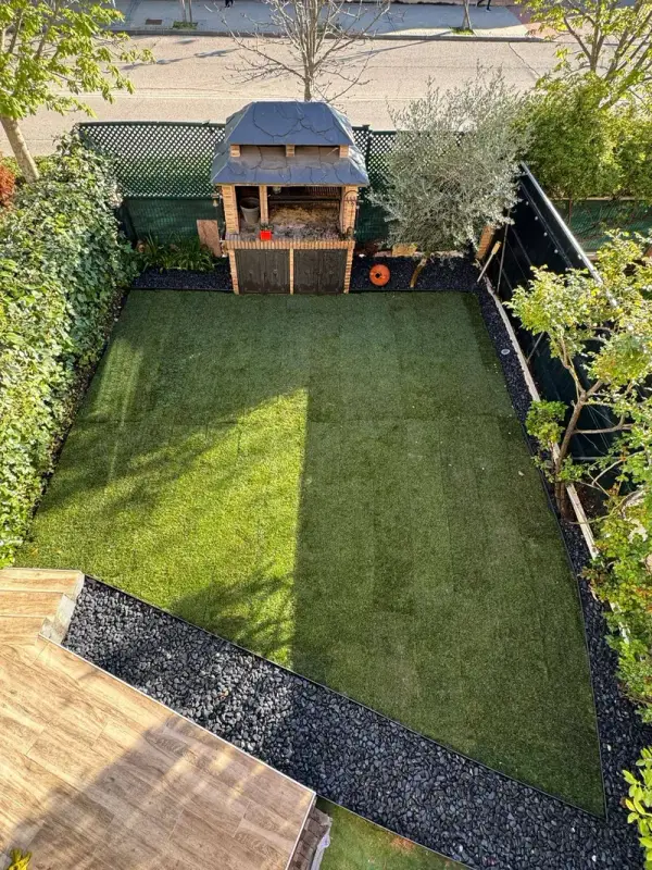 Vista superior de jardín trasero con césped, borde de grava gris y barbacoa