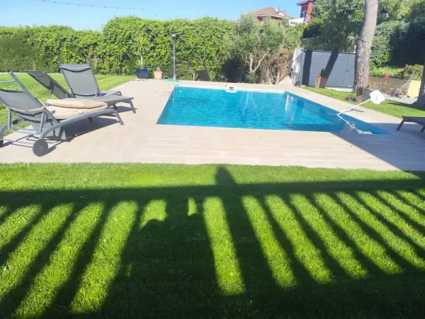 Piscina privada con tumbonas y césped natural alrededor