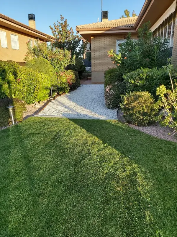 Jardín de chalet con césped natural, camino de grava y arbustos